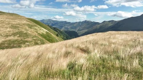Aerial view of a wide mountain valley featuring yellow dry grasslands in the foreground