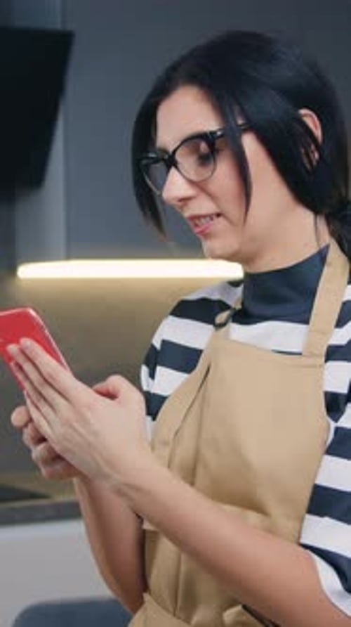 Woman using smartphone in modern kitchen setting