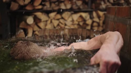 Homme athlétique plongeant dans une casserole avec de l'eau froide après un sauna, contraste de température, centre de spa