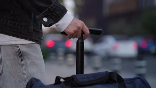 Person Rolling Luggage on City Street