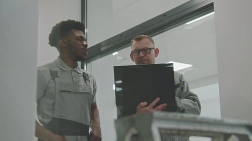 Men Discussing Laptop in Brightly Lit Office