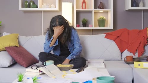 Stressed Adult Sits Amidst Clutter in Home