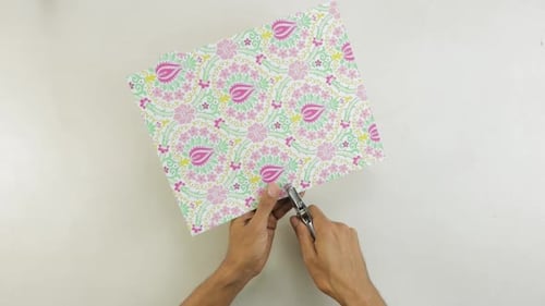 Hands Punching Holes in Decorative Paper