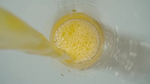 Pouring Bright Orange Juice Into Glass From Above
