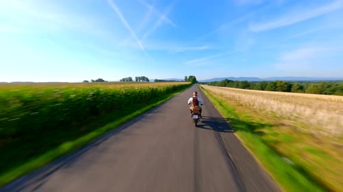 FPV Of Vintage Motorcycle Riding a Country Road Throught Fields In Summer
