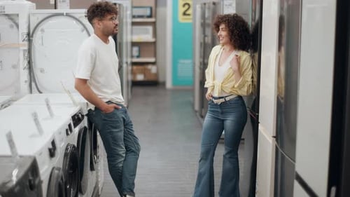 Young couple choosing washing machine in electronics store in slow motion