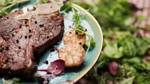 Gegrilltes T-Bone-Steak, das sich auf dem Tisch dreht, mit frischem Grün