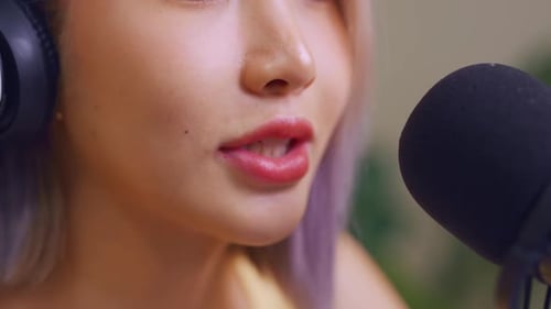 Close up of audio DJ woman sing a song on microphone to broadcasting.