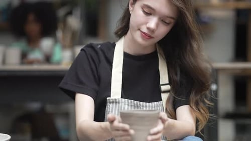 Young women is making earthenware at workshop.