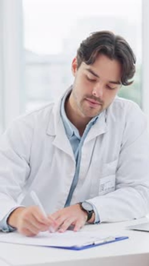 Doctor at Desk Writing Prescription in Clinic