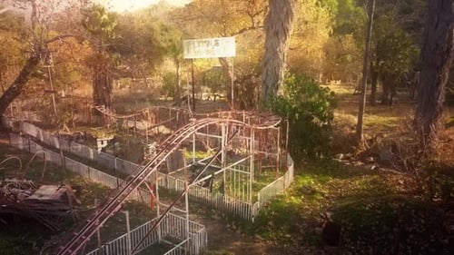 Slow drone showing the ruins of an abandoned roller coaster at an old carnival