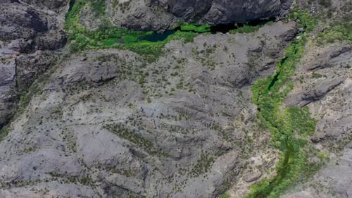 Drohne fliegt direkt über einer Schlucht, an deren Grund ein Fluss fließt