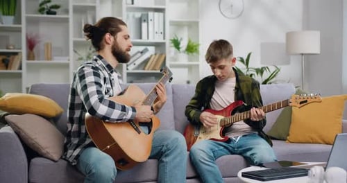 Young Adult and Teen Play Guitars Together