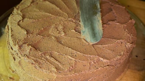Frosting and decorating a chocolate cake with coffee-chocolate frosting, top view, slow motion