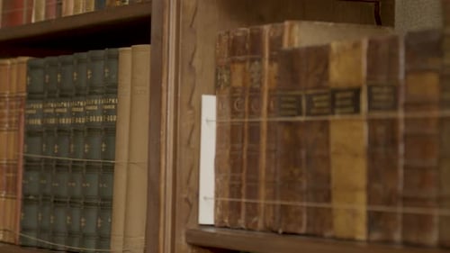 Close pan over collection of old books in luxurious private library