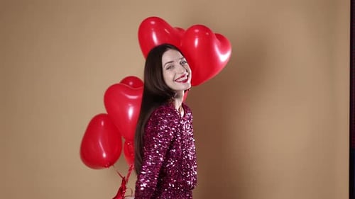 St. Valentine's Day. Beautiful woman with heart shaped balloons on beige background