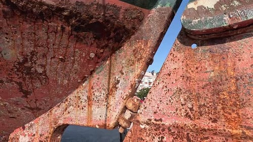 Engine propeller and rudder of thick rusty metal of old fishing boat stranded in harbor to be repair