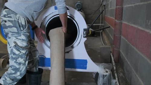 Specialist Loads a Rolled Up Carpet Into the Centrifuge for Moisture Extraction