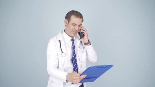 Doctor Talking on Phone While Holding Clipboard