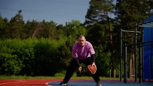 Man Dribbling Basketball on Outdoor Court