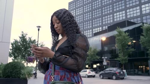Stylish young woman uses smart phone on city sidewalk