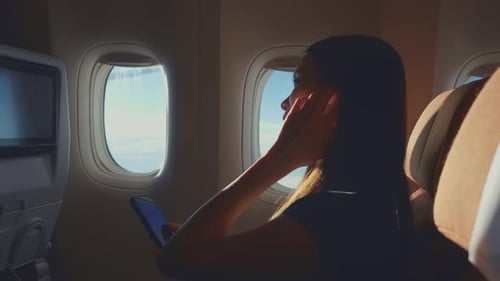 Asian woman using headphone listen to music while sitting in airplane.