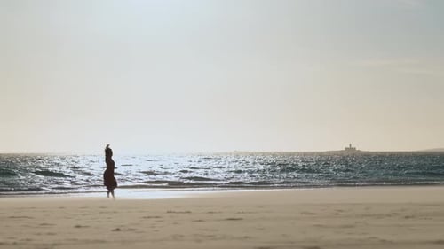 Graceful Young Woman in Red Dress Dancing Alone on the Beach at Early Sunset