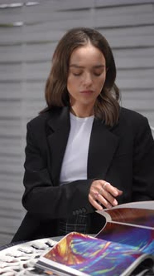 Elegant Businesswoman Sitting Outdoors Reading a Colorful Magazine