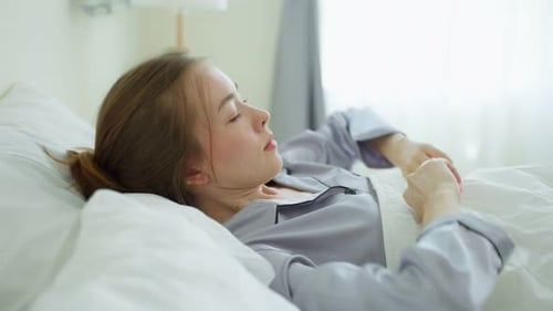 Auburn haired woman waking up in bed