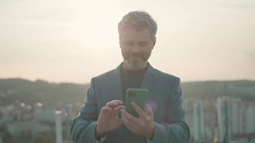 Adult Successful Lucky Businessman in Formal Outfit Holding Smartphone Texting Messages and Reading