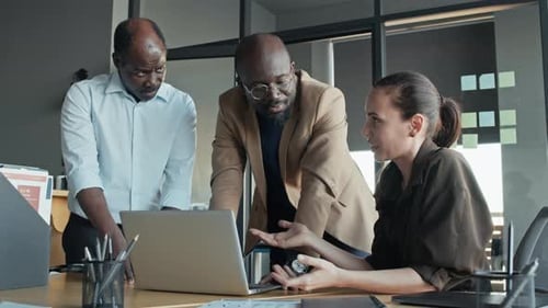 Team Collaboration Around Laptop in Modern Office