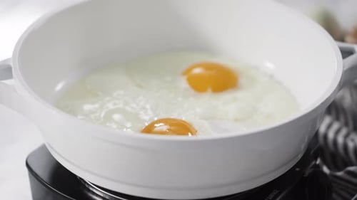 Time Lapse Close Up View Frying Farm Fresh Eggs in a White Skillet