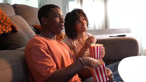 Young couple enjoying movie night with popcorn