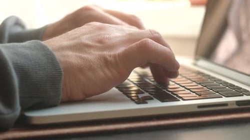 Dedos masculinos se movem sobre o teclado do laptop no escritório