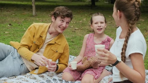 Parents and Daughter Having Talk during Picnic in Park