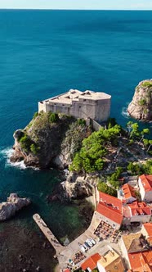 aerial portrait drone shot approaching fort lovrjenac on blue mediterranean Adriatic Sea with cliffs