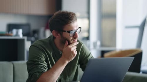 Man Contemplates Laptop Screen at Home