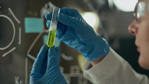 Un scientifique et une fille médecin regardent une fiole en verre contenant un liquide brillant Dans un centre de recherche moderne Young