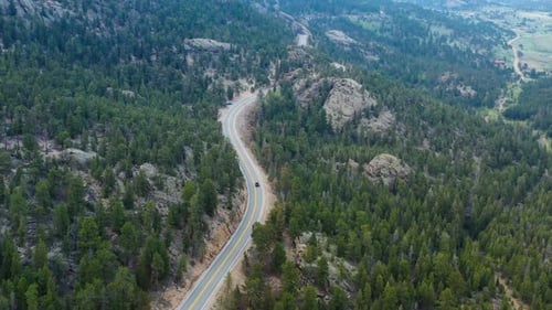 A car drives along a winding road in the Colorado mountains