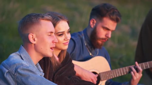 Friends Playing Guitar in Park at Sunset