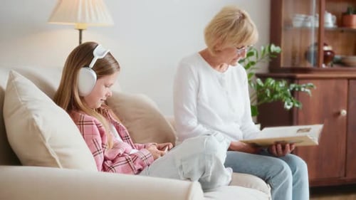 Girl with Headphones and Woman Reading on Couch