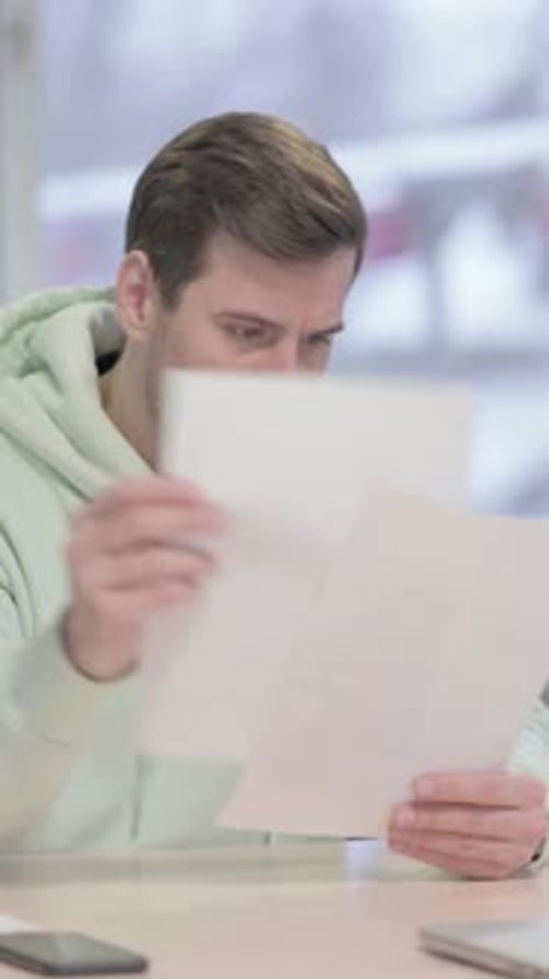 Young Man Celebrating Success while Reading Documents in Office, vertical video