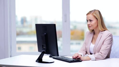 Young businesswoman typing at computer in modern office workplace