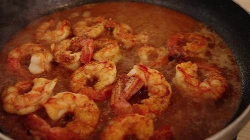 Delicious peeled shrimps simmering and boiling on hot pan, reducing and absorbing juicy flavours of