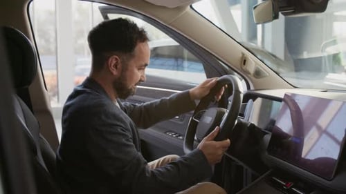 Man Sits in Car, Turns Steering Wheel, Smiles