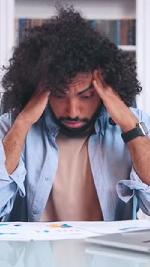 A Man Struggles with Stress While Working at His Desk in a Cozy Office