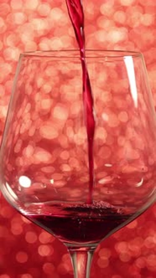 Pouring Red Wine into Glass with Red Bokeh