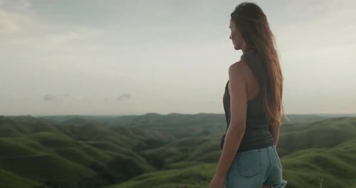 Woman Standing on Lush Green Hillside