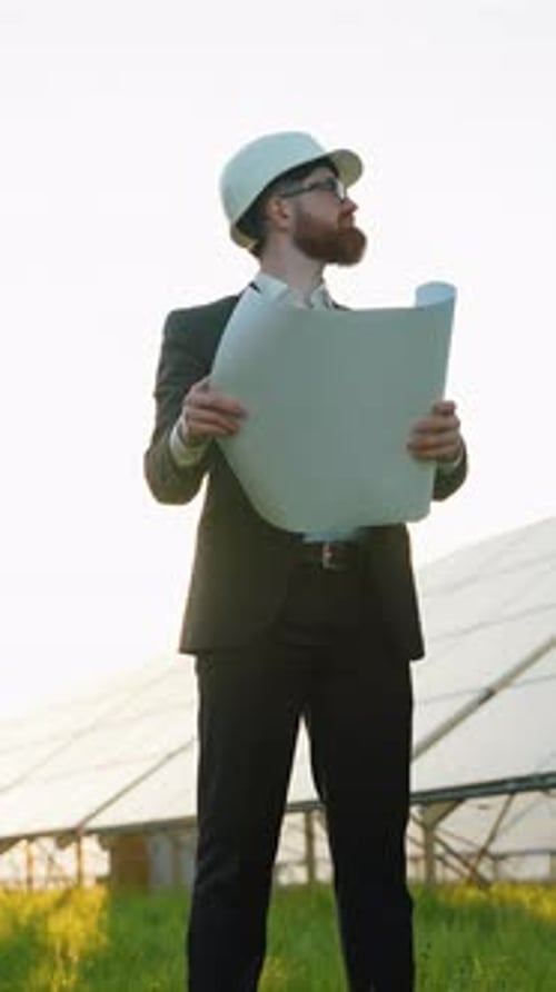 Irish Engineer Holding Blueprints Inspecting Solar Panel Farm