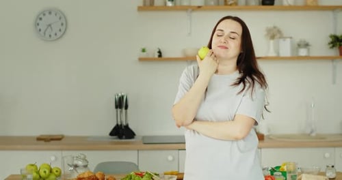 Happy Woman with Green Apple in Kitchen
